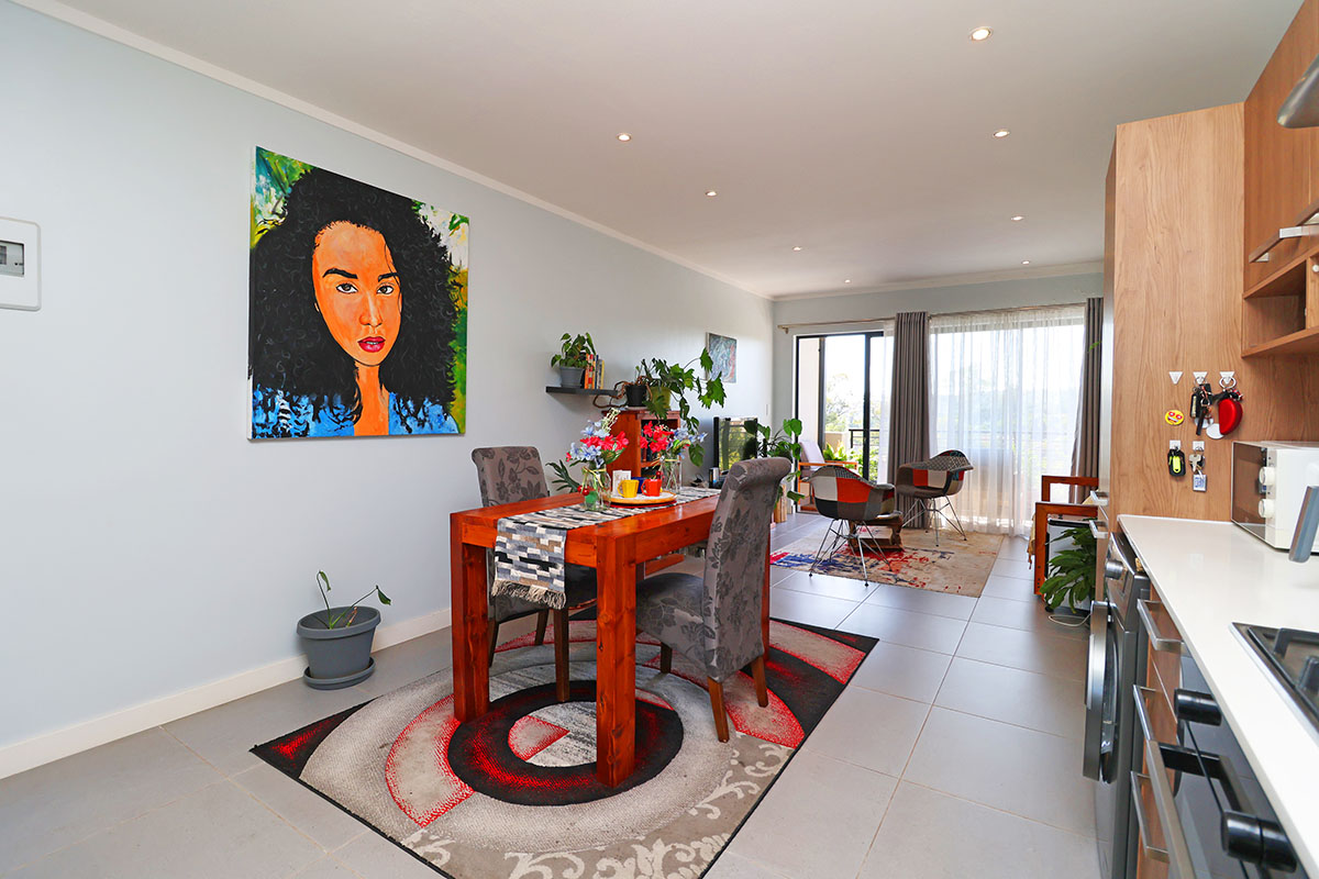 An open-plan living and dining area featuring tiled floors, recessed lighting, and a modern kitchen with built-in cabinetry and stone countertops.
