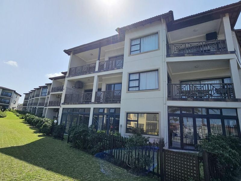 A view of the apartment complex exterior featuring multi-level balconies, large windows, and well-maintained landscaped grounds.