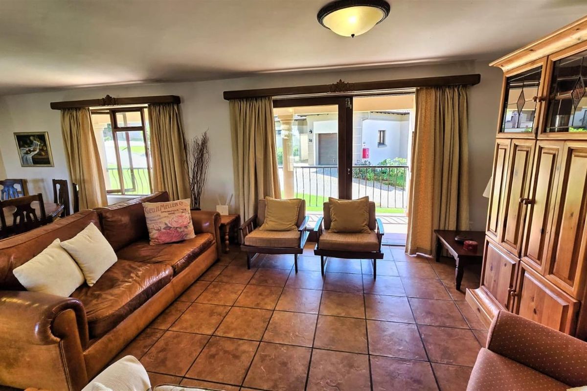 Spacious living area featuring terracotta floor tiles, large windows, and sliding glass doors providing access to an outdoor balcony.