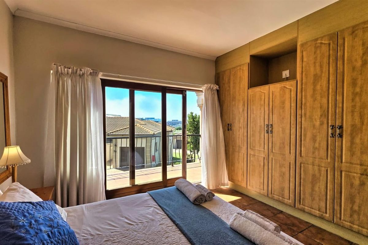 A bedroom featuring built-in wooden cabinetry and sliding glass doors that open onto a balcony with exterior views.