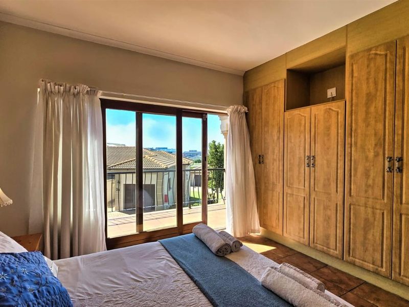 A bedroom featuring built-in wooden cabinetry and sliding glass doors that open onto a balcony with exterior views.
