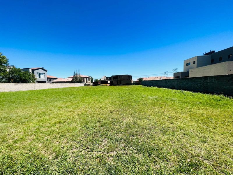 A vacant residential plot featuring a level grass lawn enclosed by perimeter boundary walls in a developed neighborhood.