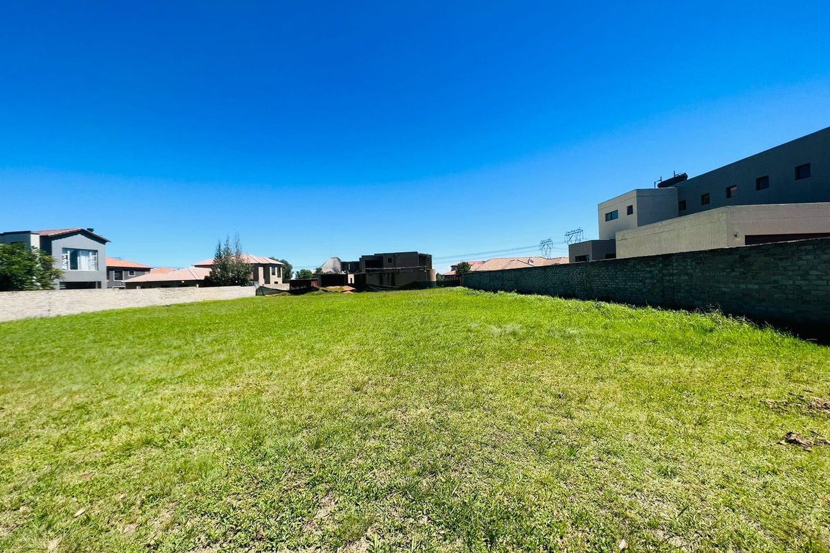 A vacant residential plot featuring a level grass lawn enclosed by boundary walls, situated within a developed neighborhood.