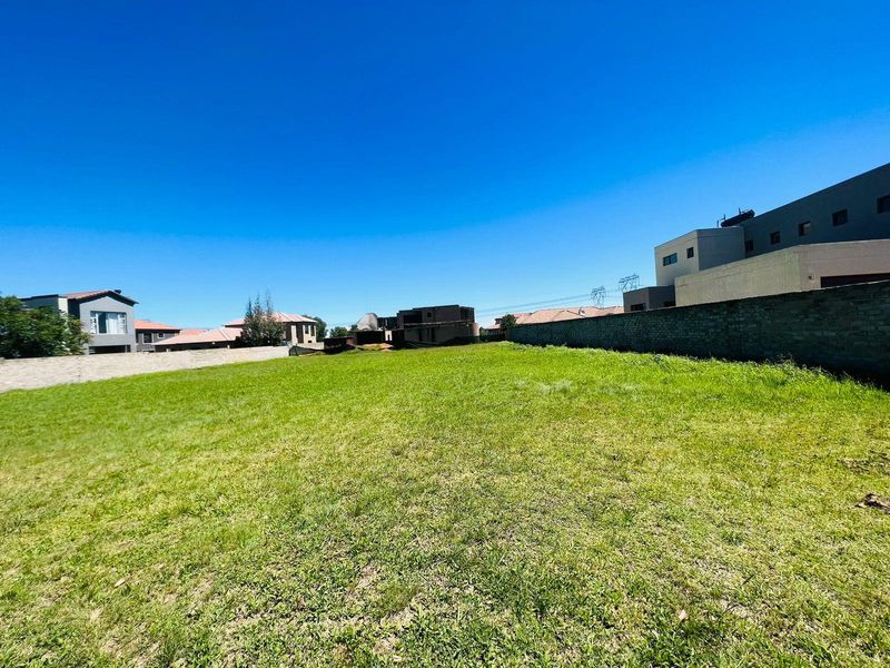 A vacant residential plot featuring a level grass lawn enclosed by boundary walls, situated within an established residential neighborhood.