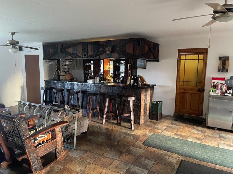 A rustic-style built-in home bar area featuring dark wood cabinetry, tiled flooring, and a ceiling fan, providing a dedicated space for entertaining.