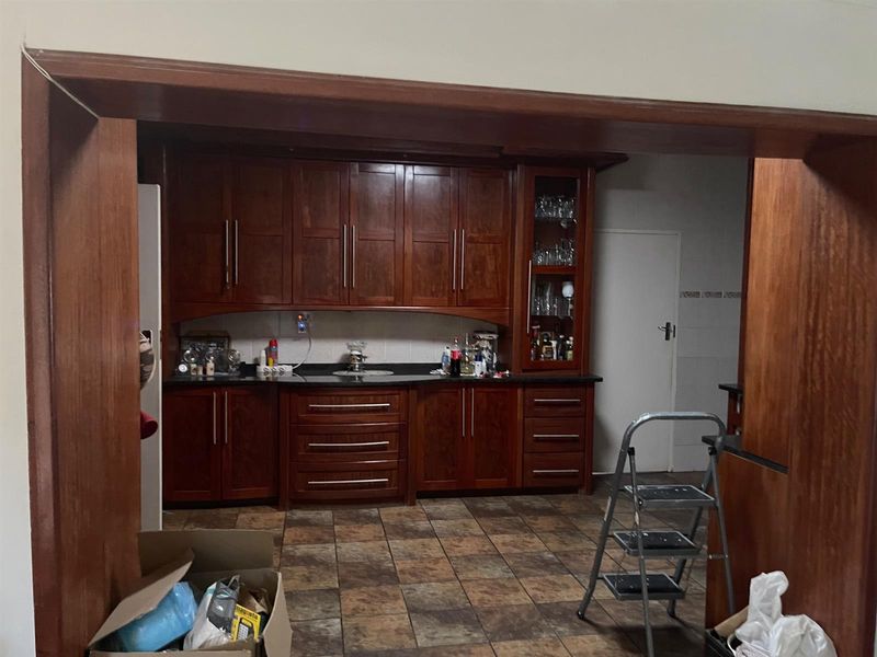 A kitchen featuring dark wood cabinetry, granite countertops, and tiled flooring, viewed through a wooden archway.