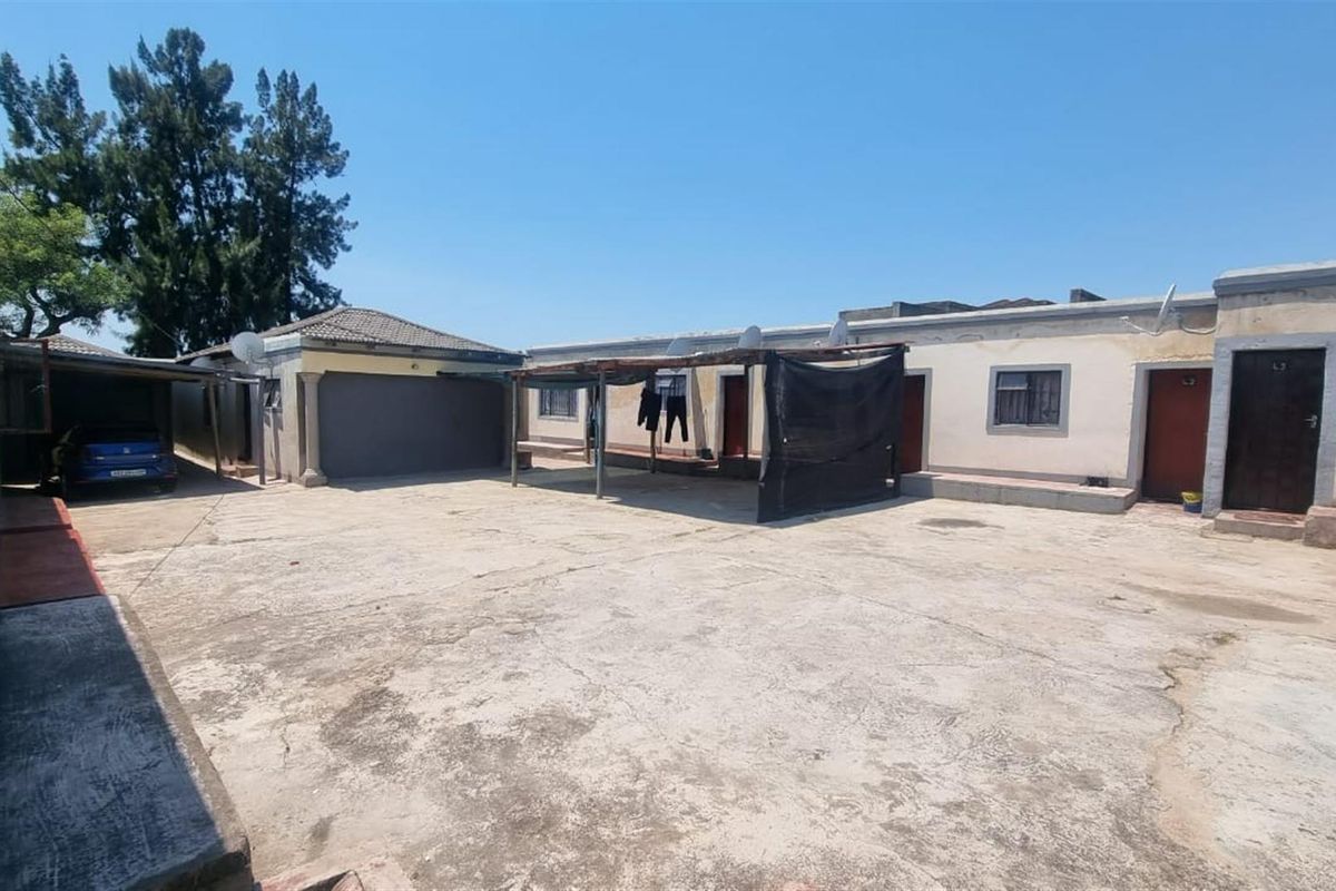 Spacious industrial-style rear courtyard featuring a concrete driveway, covered outdoor area, and access to multiple units and a garage.