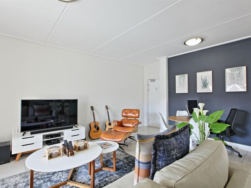 A bright and well-maintained living room featuring neutral walls, a dark accent wall, and tiled flooring, providing a comfortable and functional living space.