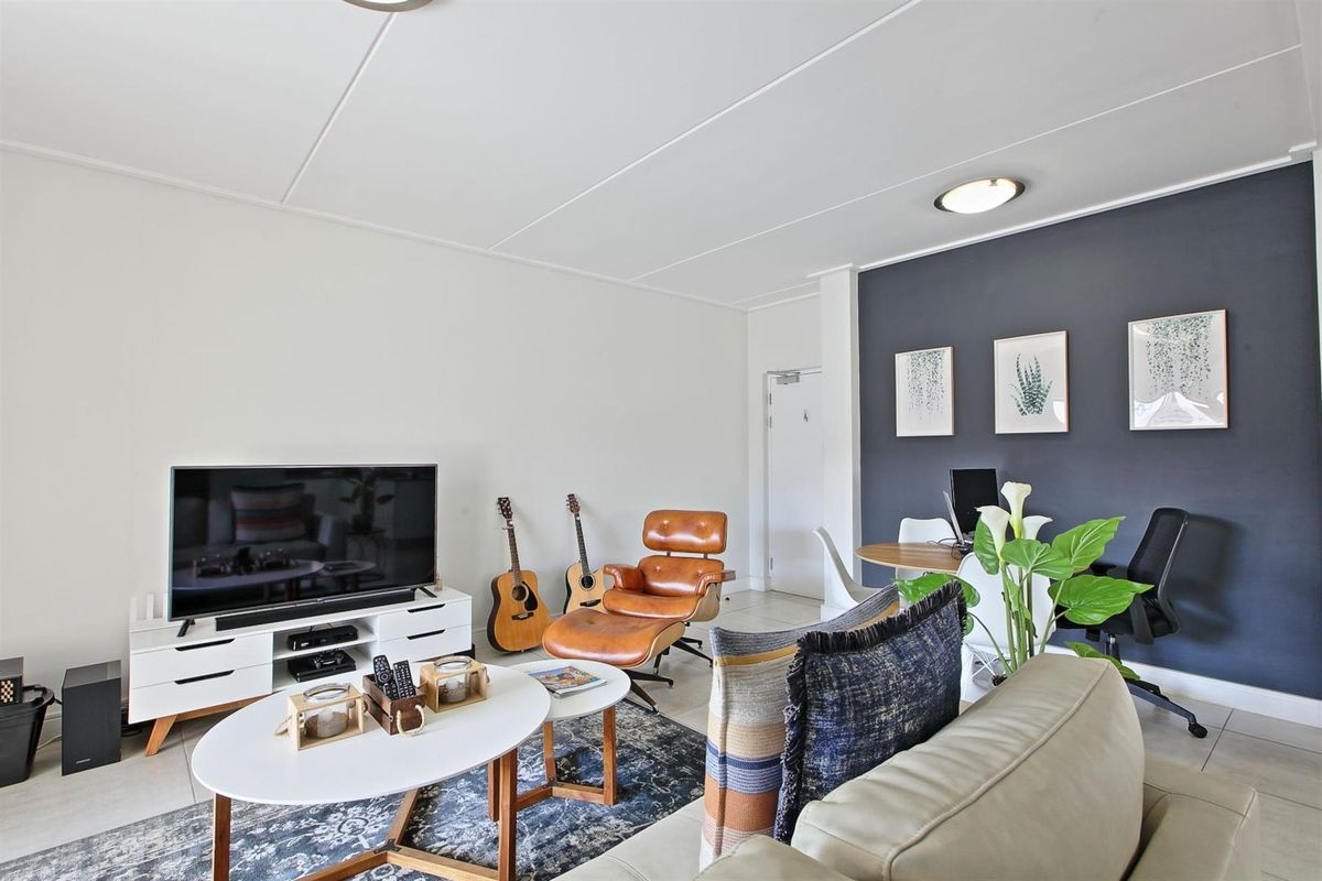 A bright and well-maintained living room featuring neutral walls, a dark accent wall, and tiled flooring, providing a comfortable and functional living space.