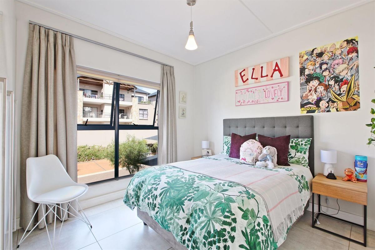 A bright and well-maintained bedroom featuring tiled flooring, a large window with curtain tracks, and a modern pendant light fixture.
