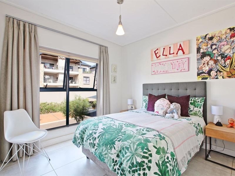 A bright and well-maintained bedroom featuring tiled flooring, a large window with curtain tracks, and a modern pendant light fixture.