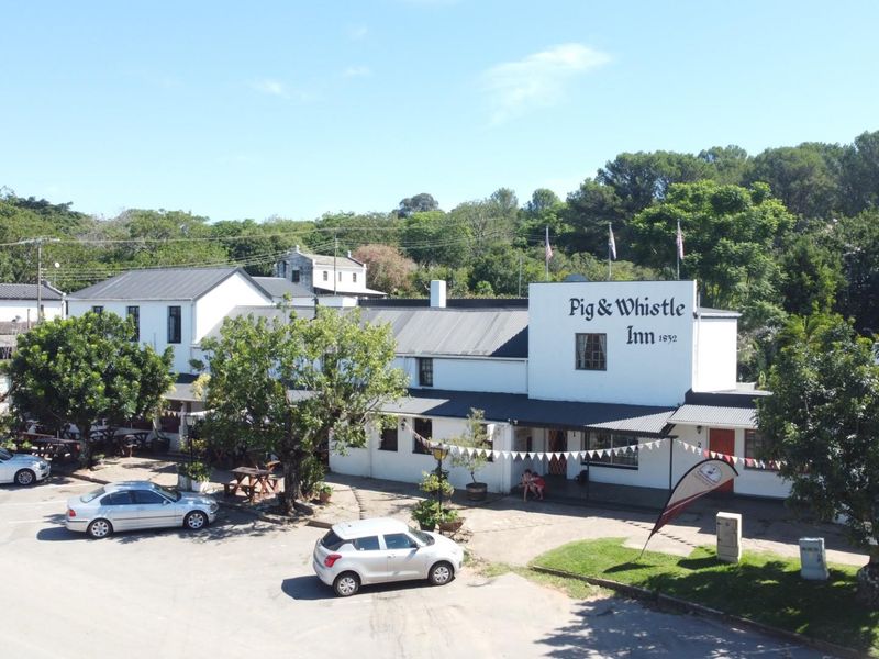 Aerial view of the historic Pig & Whistle Inn, showcasing the main building facade, surrounding grounds, and parking area.