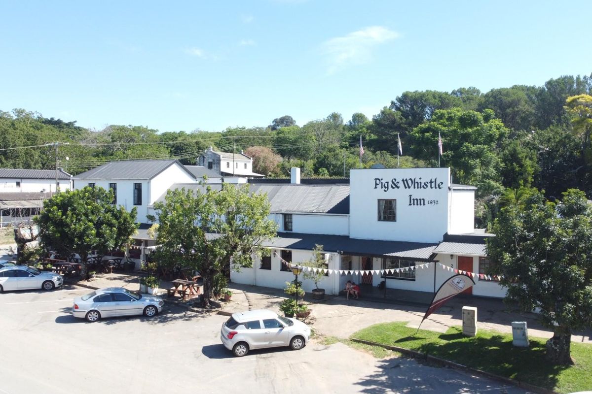 Aerial view of the historic Pig & Whistle Inn, showcasing the main building facade, surrounding grounds, and parking area.