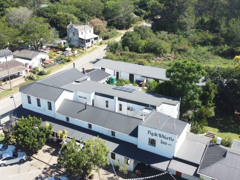 Aerial view of the Pig & Whistle Inn, showcasing the building's layout, metal roofing, solar panels, and surrounding grounds.