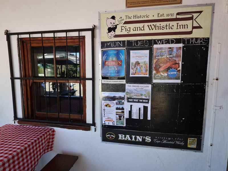 A rustic hotel entrance area featuring a wooden window with security bars and a large information notice board for guests.