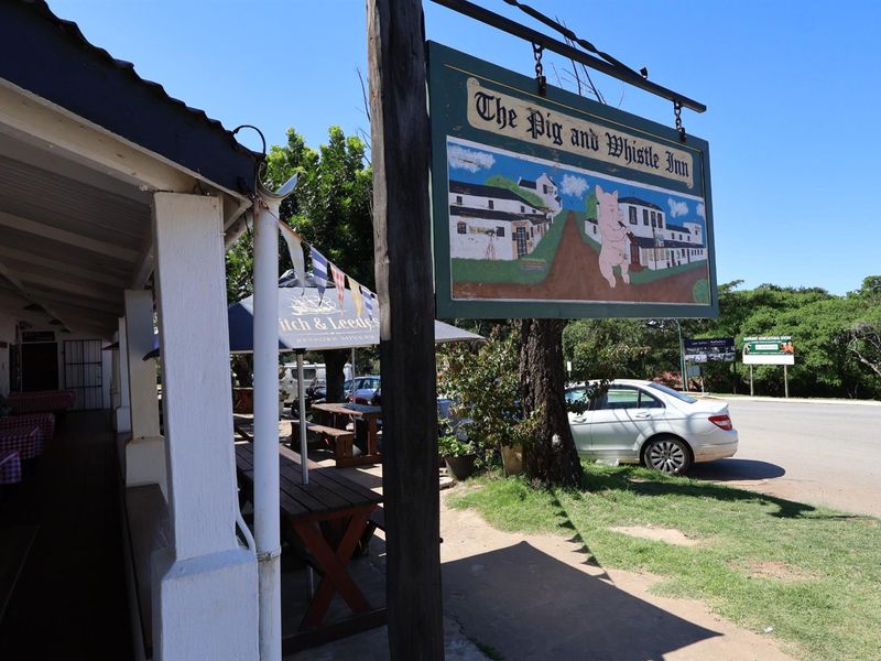 Exterior view of The Pig and Whistle Inn featuring a covered patio area and prominent roadside signage.