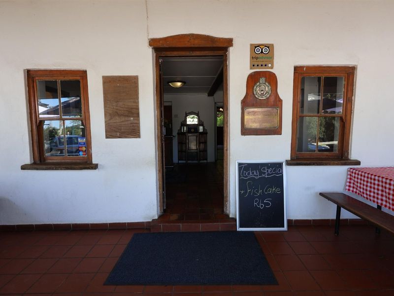 Entrance facade of a hotel featuring a tiled patio, timber-framed windows, and a central doorway leading into the interior.