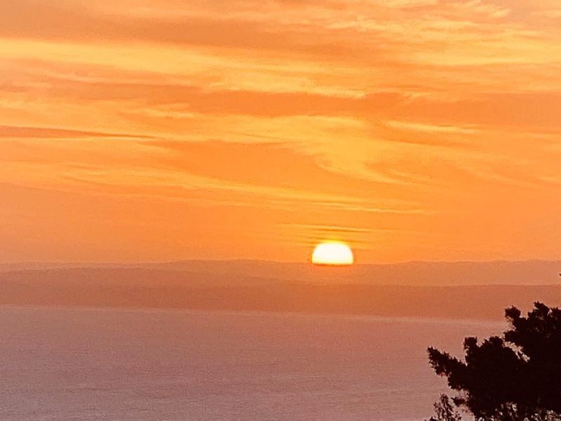 A scenic view of the sunset over the horizon, highlighting the natural landscape and coastal setting of the property.