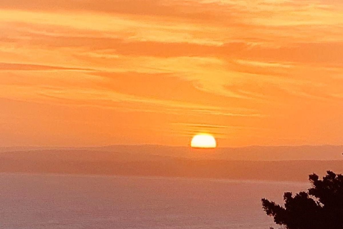 A scenic view of the sunset over the horizon, highlighting the natural landscape and coastal setting of the property.
