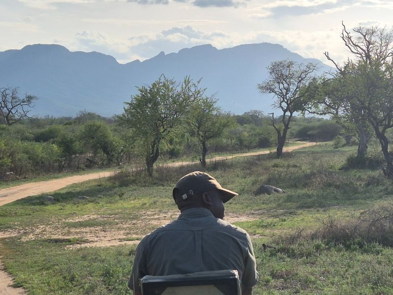 A scenic landscape view featuring natural terrain, dirt paths, and distant mountain ranges.