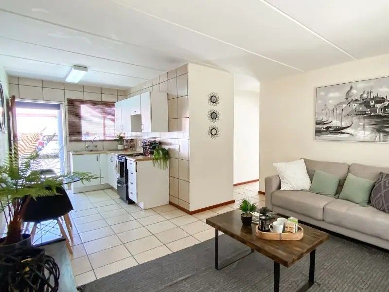 Open-plan living area featuring a functional kitchen with tiled flooring, cabinetry, and a built-in stove, seamlessly connected to the main living space.