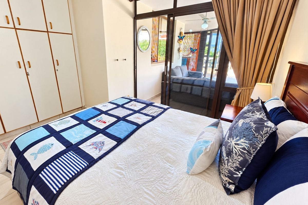 A bedroom featuring built-in cupboards, tiled flooring, and sliding glass doors that provide access to an adjoining patio area.