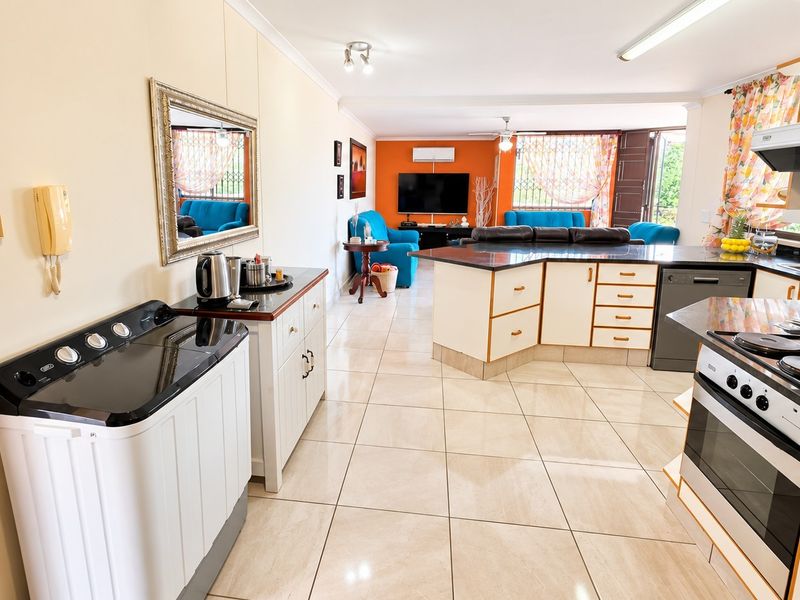 Spacious open-plan living area featuring a functional kitchen with granite countertops, built-in oven, hob, and tiled flooring throughout.
