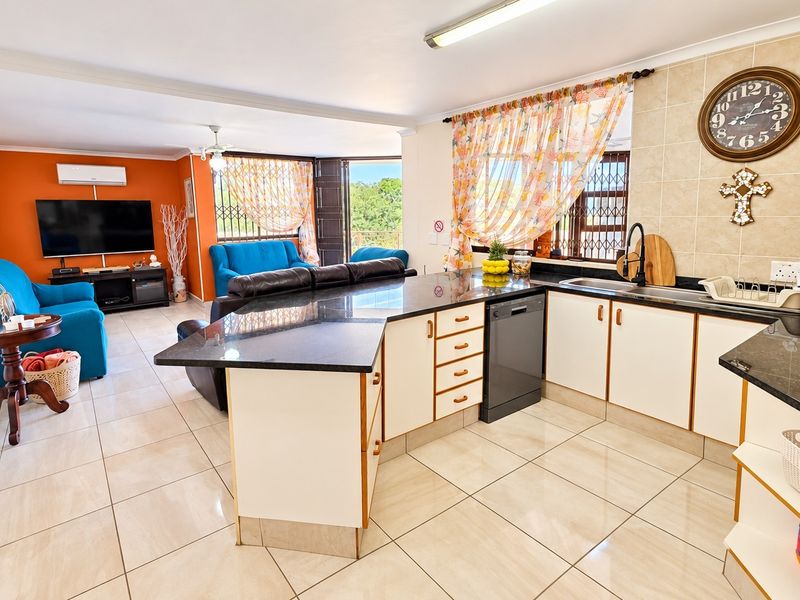 Spacious open-plan living and kitchen area featuring granite countertops, tiled flooring, and a split-system air conditioner, offering a functional and connected layout.