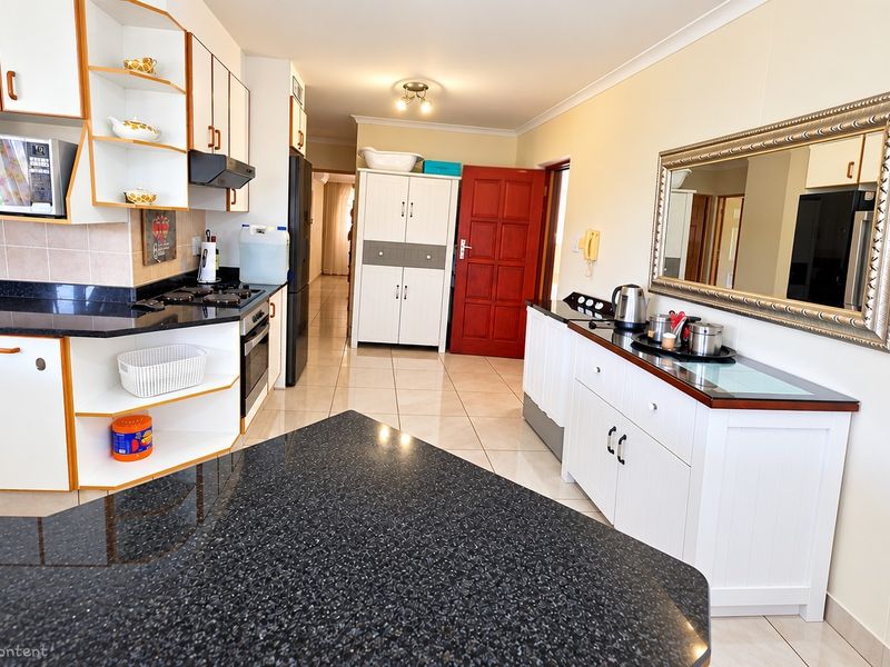 A functional kitchen featuring granite countertops, built-in cabinetry, and tiled flooring, offering a practical layout with integrated cooking appliances.