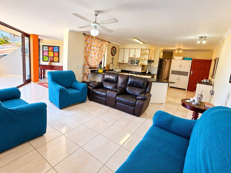 Spacious open-plan living area featuring tiled floors, a modern kitchen with granite countertops, and large sliding doors leading to an outdoor balcony.