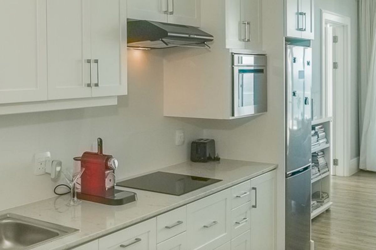 Modern kitchen featuring white shaker cabinetry, stone countertops, integrated appliances, and a sleek induction hob in a clean, contemporary design.