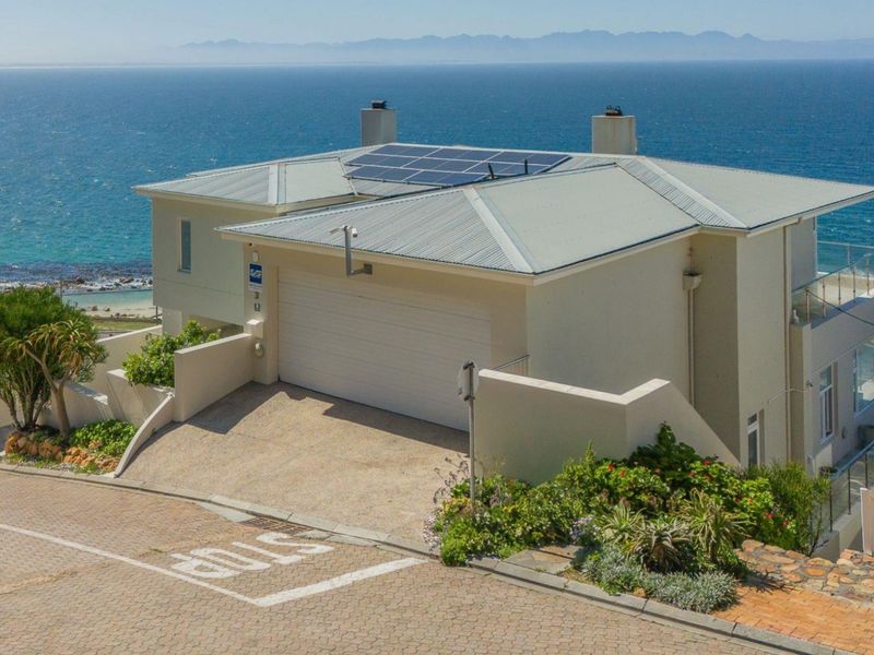 Front elevation of a coastal property featuring a double garage, solar panel installation, and paved driveway with ocean views.