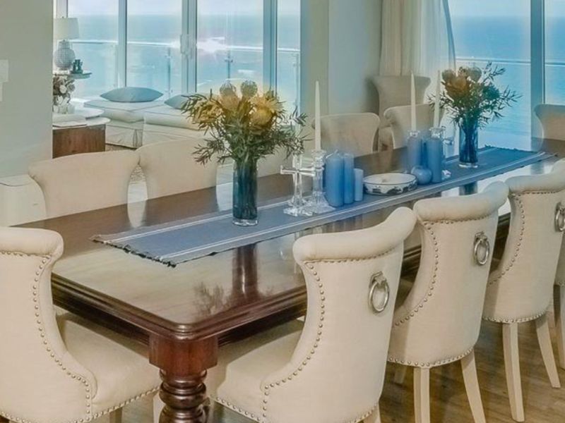 Elegant dining room featuring hardwood flooring and expansive floor-to-ceiling glass sliding doors offering panoramic ocean views.