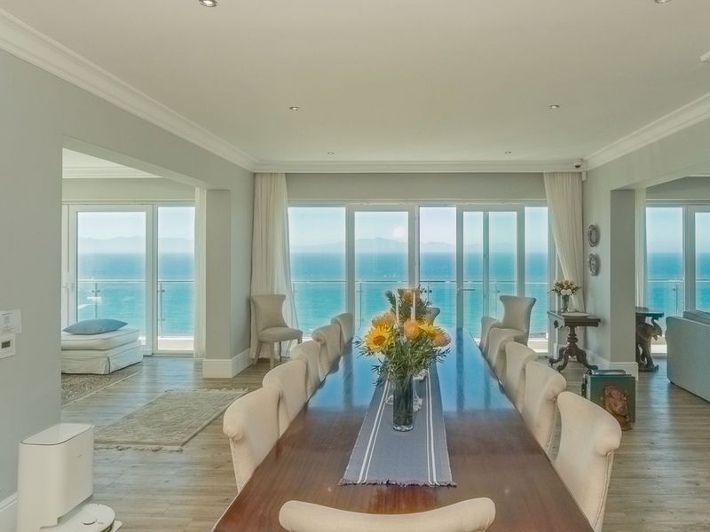 Spacious open-plan dining area featuring modern laminate flooring, recessed lighting, and expansive sliding glass doors offering panoramic ocean views.