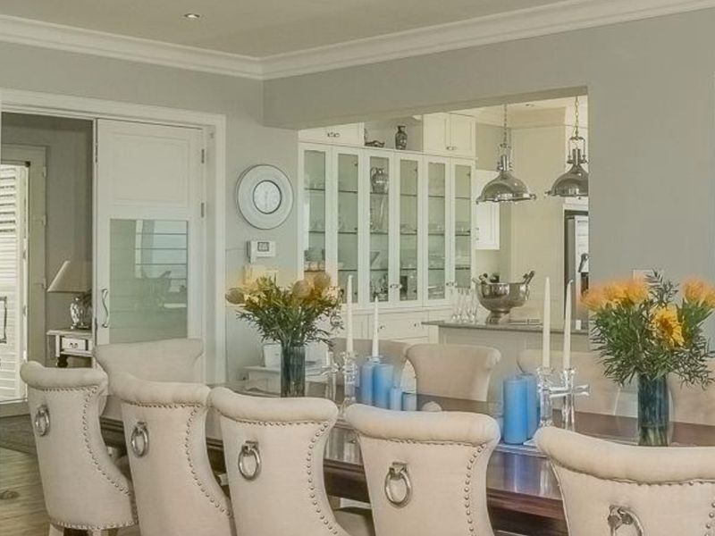 Elegant open-plan dining area featuring classic crown molding, recessed lighting, and built-in glass-fronted display cabinetry connecting to the kitchen space.