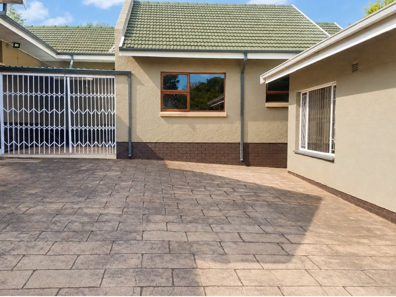 A well-maintained rear courtyard featuring paved flooring, security gates, and secure window bars, providing a clean and functional outdoor space.