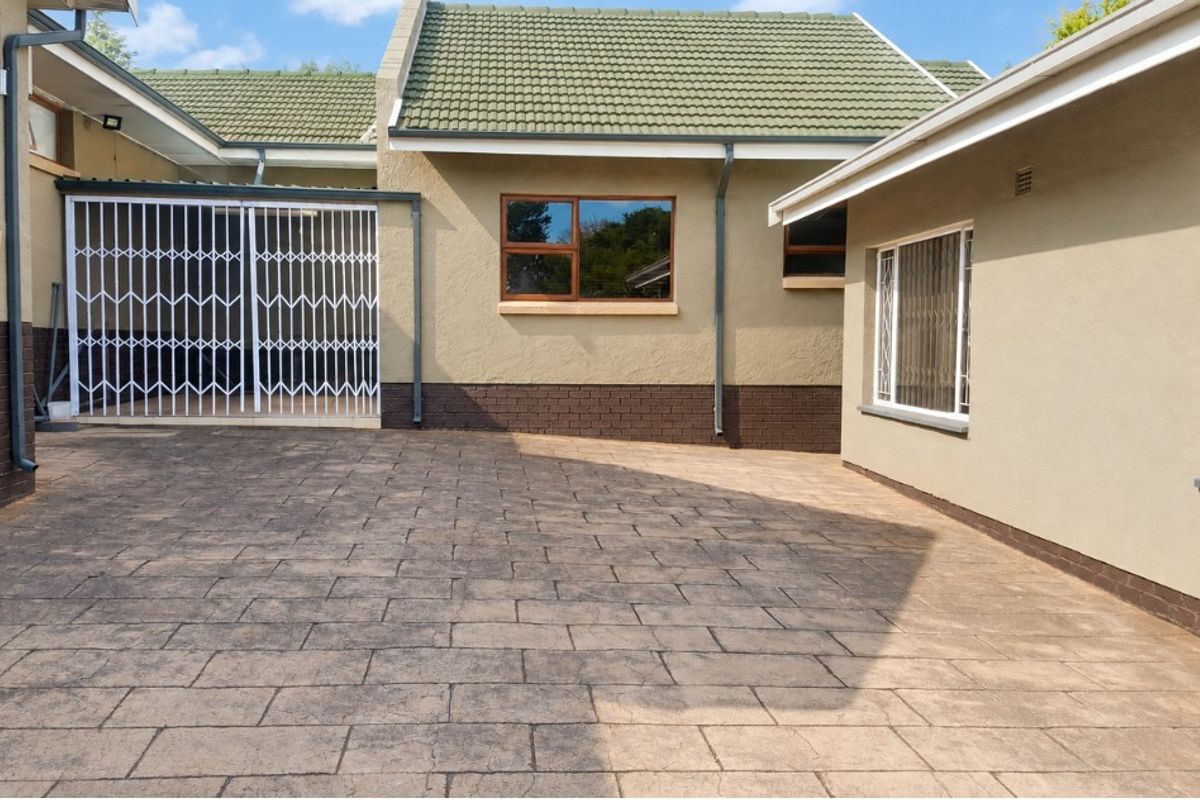 A well-maintained rear courtyard featuring paved flooring, security gates, and secure window bars, providing a clean and functional outdoor space.