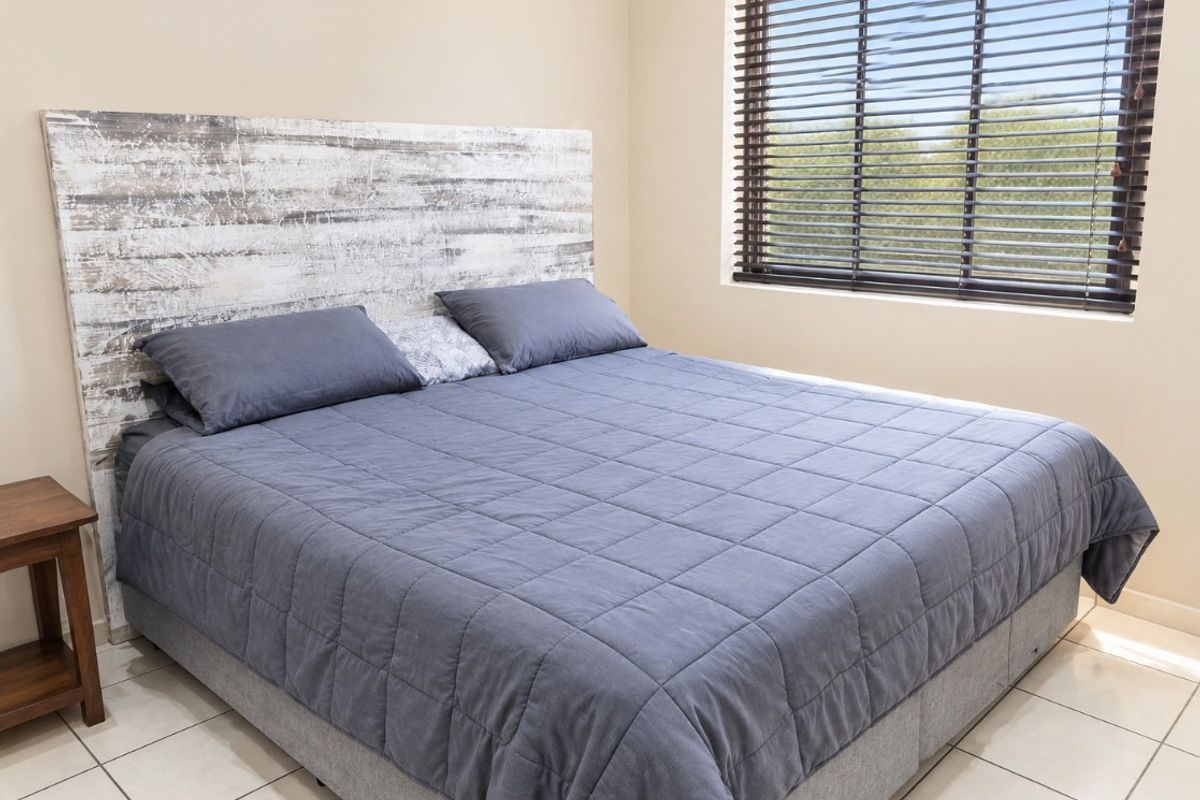 A well-maintained bedroom featuring neutral wall tones, tiled flooring, and fitted venetian blinds, providing a clean and functional living space.