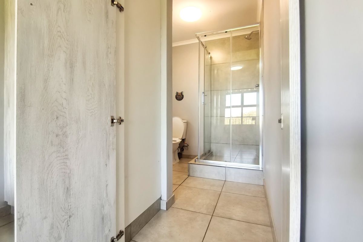 A clean and functional bathroom featuring a glass-enclosed shower, tiled flooring, and a standard toilet, presented in a neutral, well-maintained condition.