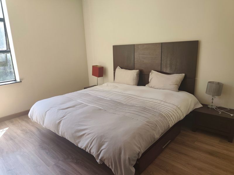 A bedroom featuring laminate flooring and a large window, providing a neutral space ready for personalization.