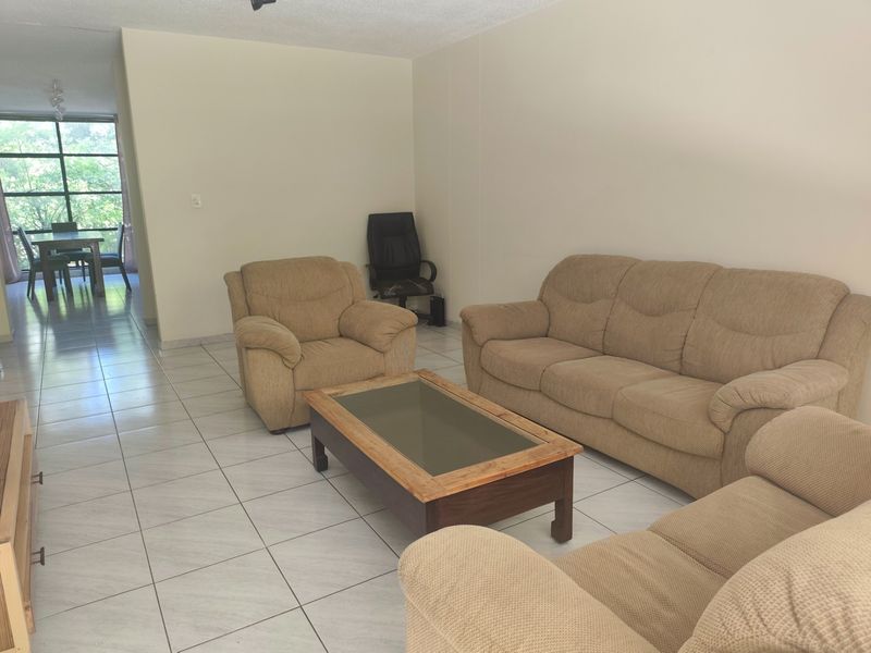 Open plan living and dining area featuring neutral tiled flooring and large windows providing natural light.