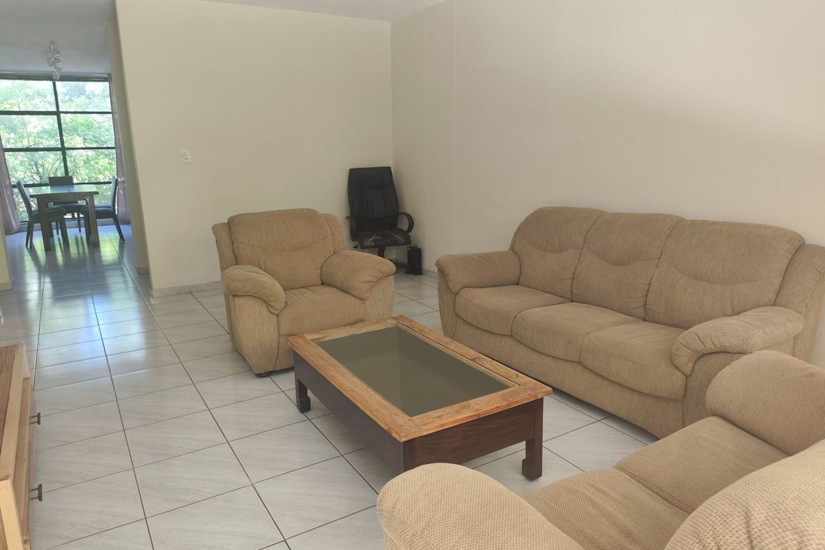 Open plan living and dining area featuring neutral tiled flooring and large windows providing natural light.