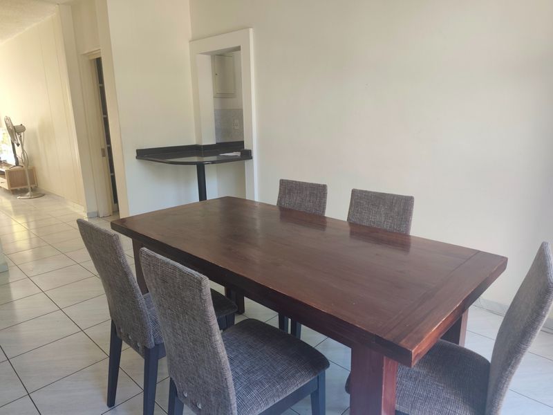 Dining area featuring tiled flooring and a convenient pass-through window with a granite breakfast bar connecting to the kitchen space.