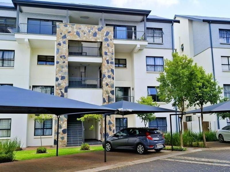 Modern apartment complex exterior featuring stone facade accents, private balconies, and dedicated shade cloth parking bays.