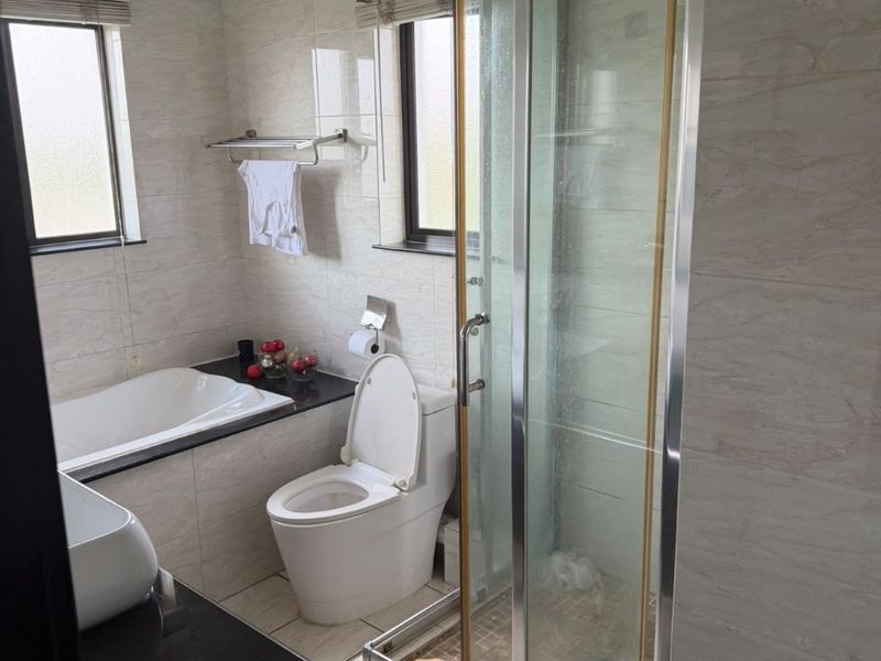 A functional bathroom featuring a built-in bathtub, a separate glass-enclosed shower, a toilet, and a vanity with a dark countertop.