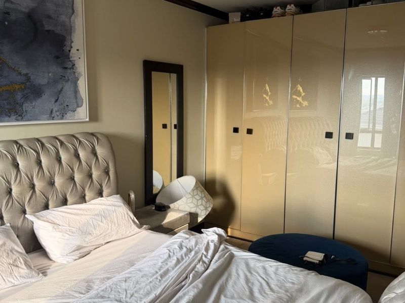 A well-maintained bedroom featuring high-gloss built-in wardrobes and decorative crown molding, providing ample storage and a clean, finished aesthetic.