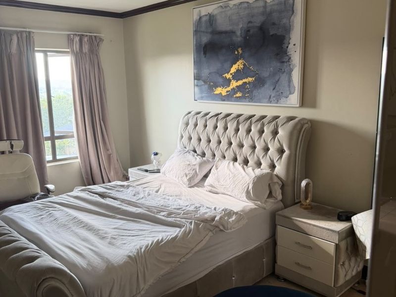 A bedroom featuring a window with curtains, crown molding, and a ceiling-mounted light fixture.