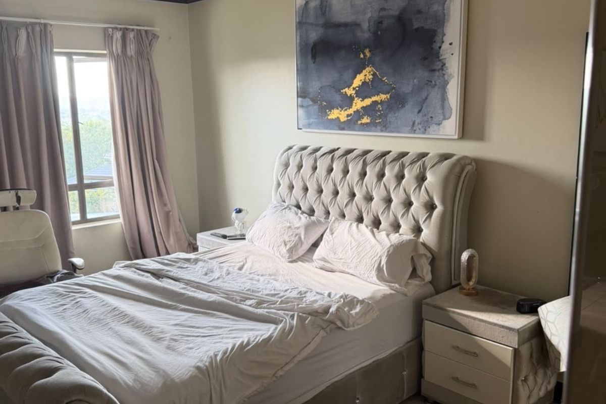 A bedroom featuring a window with curtains, crown molding, and a ceiling-mounted light fixture.