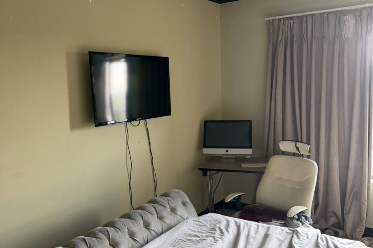 A bedroom featuring neutral wall paint, dark crown molding, and floor-to-ceiling curtains, providing a functional space with potential for aesthetic updates.