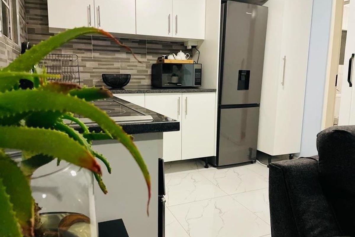 Modern kitchen featuring white cabinetry, stone-look countertops, and a decorative tiled backsplash, offering a clean and functional cooking space.
